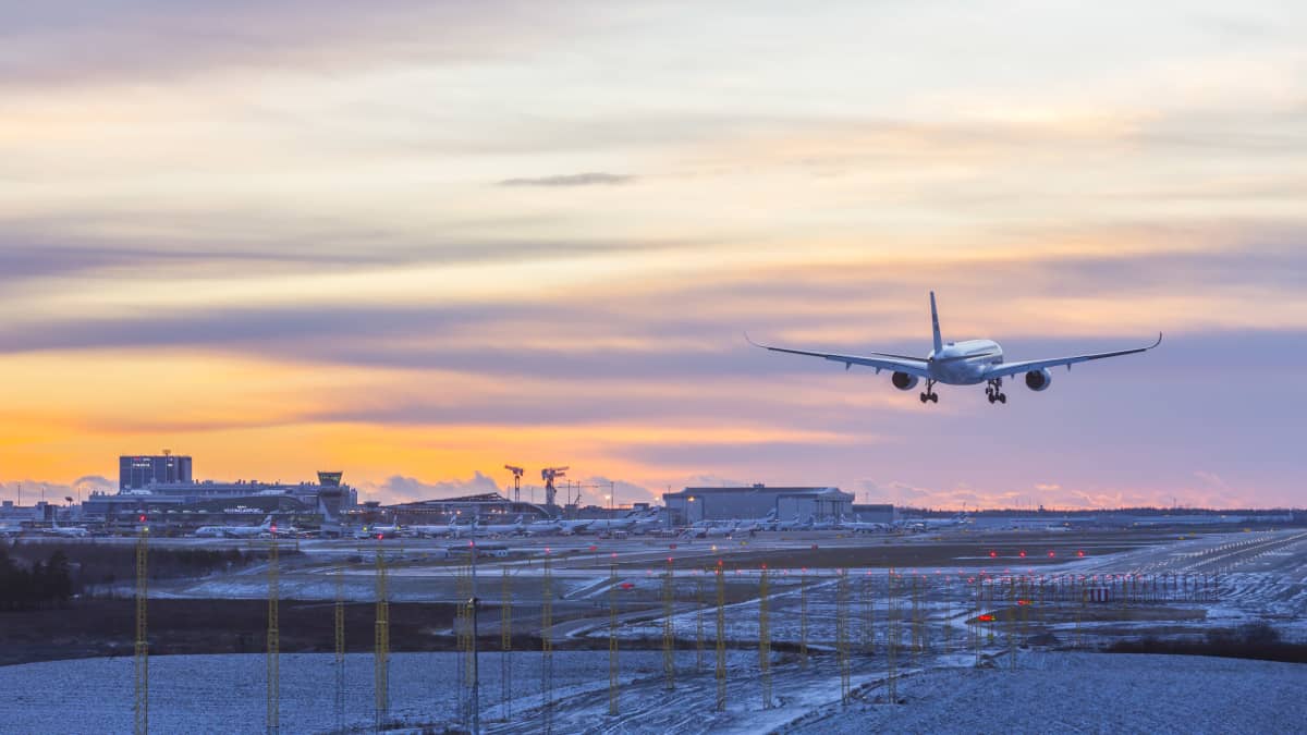 Ett Finnairflyg är på väg att landa vid Helsingfors-Vanda flygplats i solnedgången.