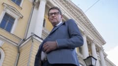 Ministeri Vanhanen poseeraa Valtionneuvoston linnan edessä.