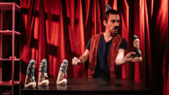 Teatteriroolissa oleva mies punaisessa liivissä esiintyy dildohahmojen kanssa. 