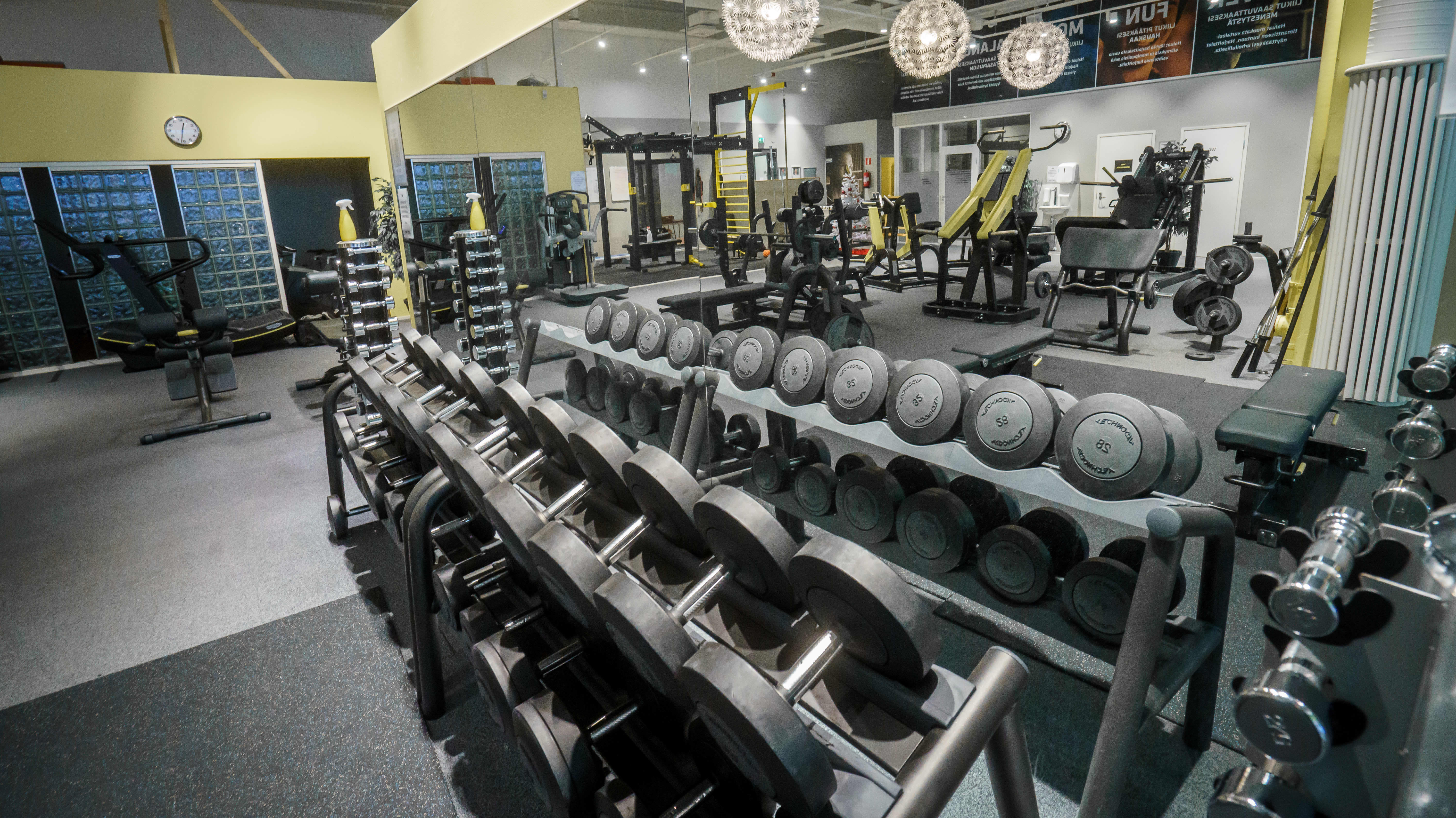 Kuntosali, etualalla käsipainoja. Salilla ei ole yhtään ihmistä.