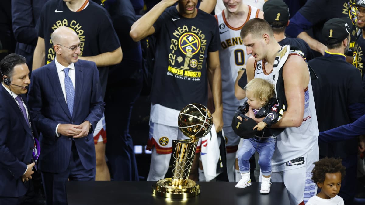Nikola Jokic ja hänen tyttärensä ihailevat NBA-pokaalia.
