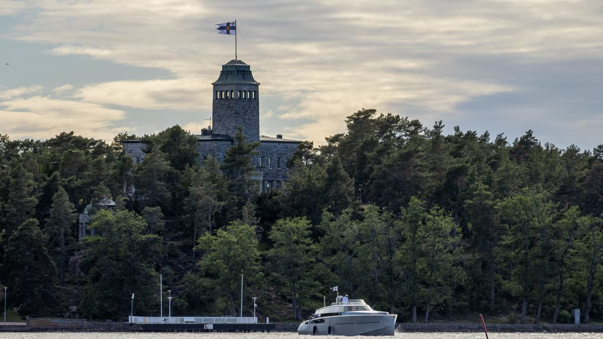 Pieni laiva Kultarannan edustalla vesillä. Rakennuksen huipulla on Suomen lippu.