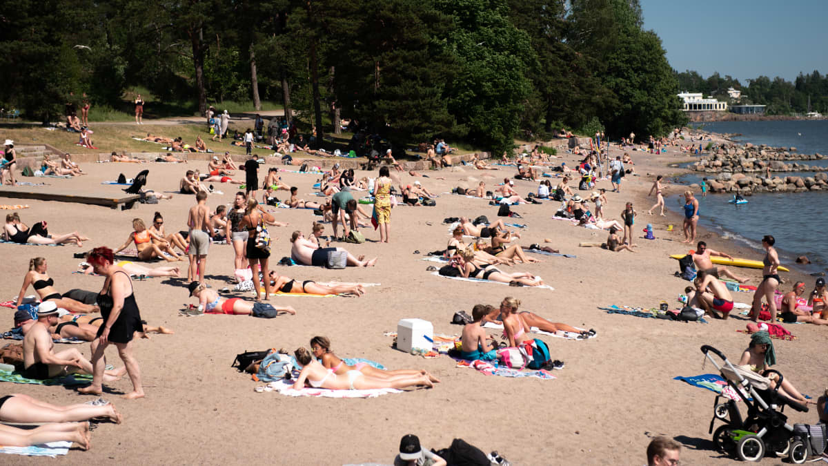 Ihmisiä ottamassa aurionkoa Mustikkamaan uimarannalla.