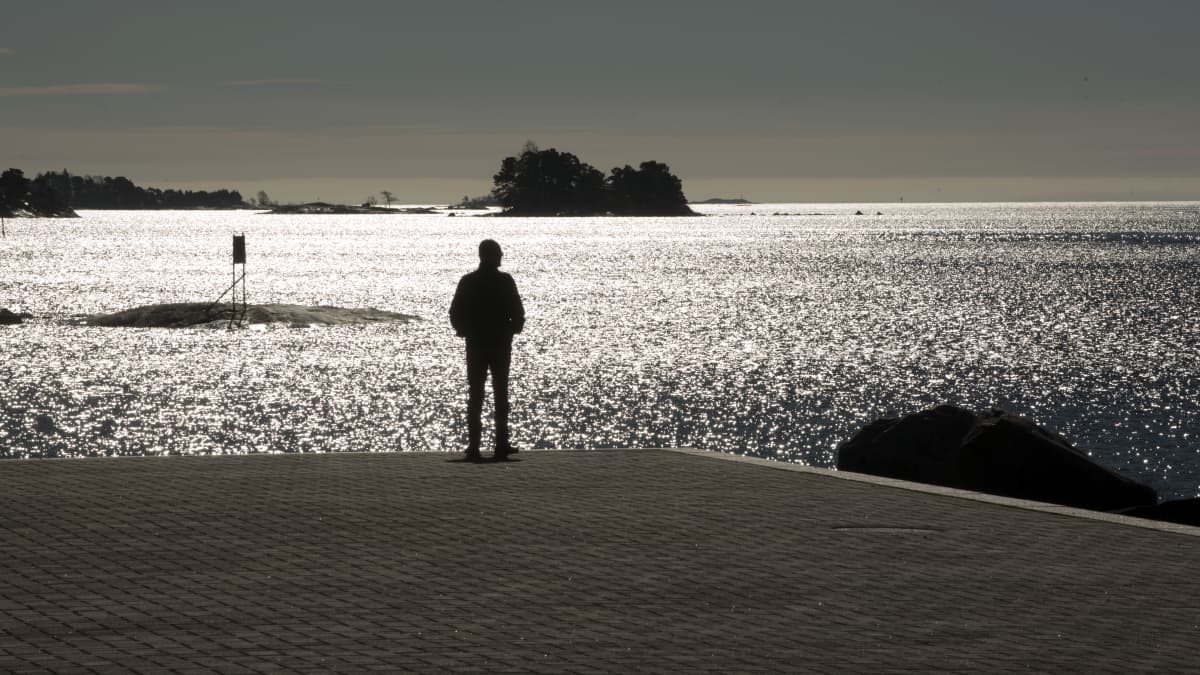 Mies seisoo meren rannalla.