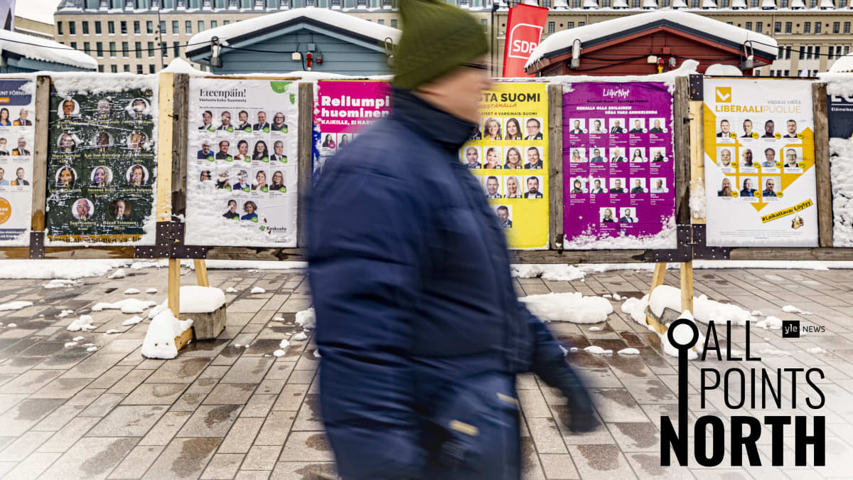 A person walks past election posters on a town square.