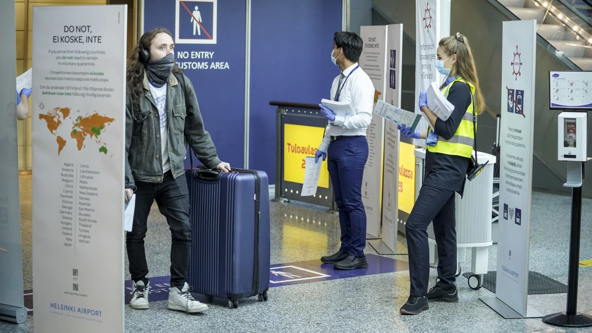 Matkustaja saapuu Helsinki-Vantaan lentoasemalle 7. elokuuta 2020. Häntä vastassa on kaksi henkilöä, joilla on ohjelehtinen Suomeen ulkomailta saapuville.