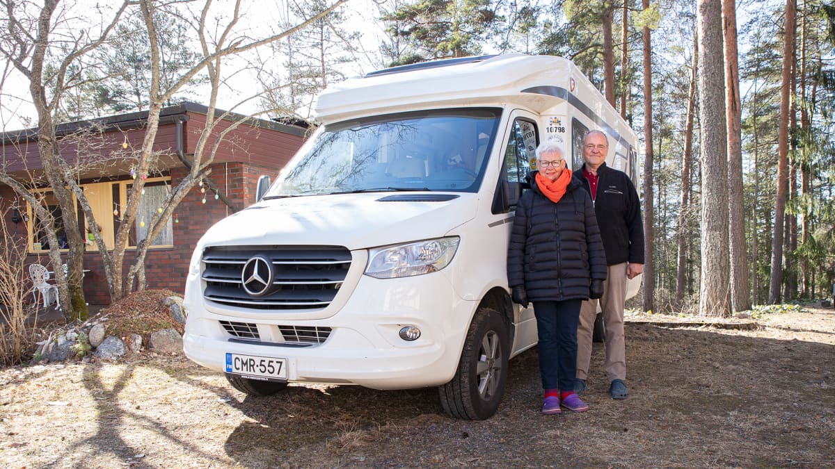 Pentti ja Pirkko Äijö poseeraavat matkailuautonsa vieressä.