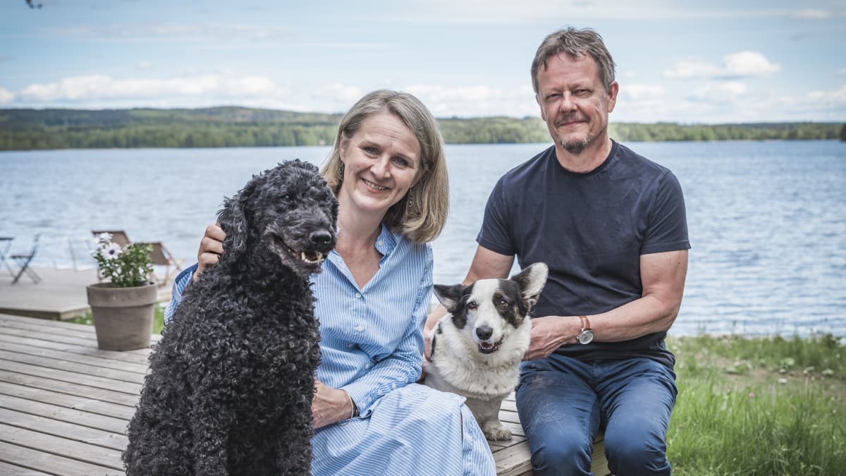 Kirsi Pohjola ja Kimmo Jokinen ja heidän koiransa järvenrannalla.