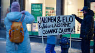 Mielenosoittajia ja vanerinen kyltti kadulla.