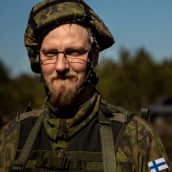 Joni Koivu katsoo kameraan lähikuvassa armeija-asussa. Koivulla on kypärä päässä ja parta. 