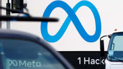Someyhtiö Metan sininen logo valkoisella pohjalla kyltissä pääkonttorin seinustalla. Etualalla ajoneuvoja.