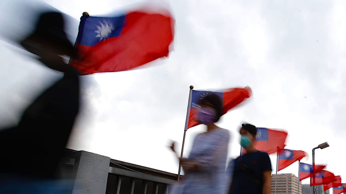Taiwanin liput liehuvat jalankulkijoiden taustalla, kun he kävelevät Taipeissa lokakuussa 2022.