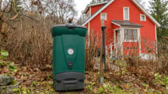 Vihreä muovikomposti seisoo syksyisessä puutarhassa omakotialueella.