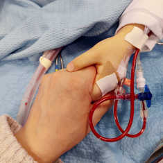 A mother holds her child's hand in the hospital. 