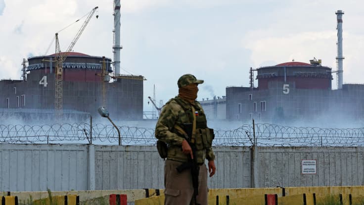 Venäläissotilas seisoo vahdissa ydinvoimalan rakennusten edessä.