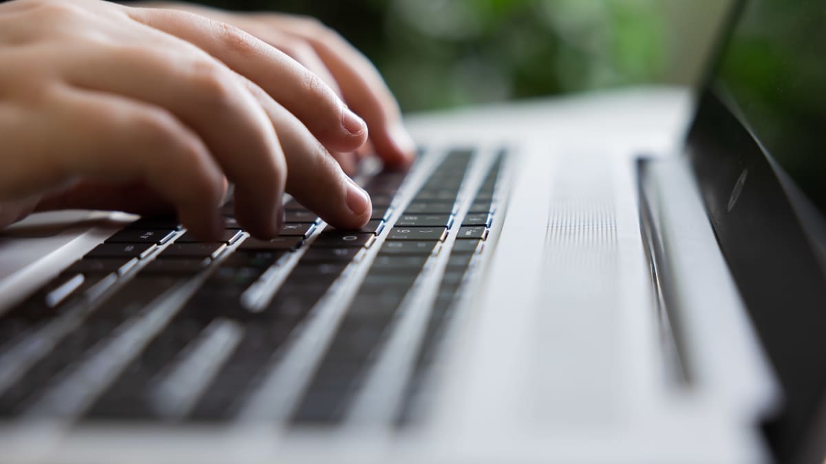 Fingers on a laptop keyboard.