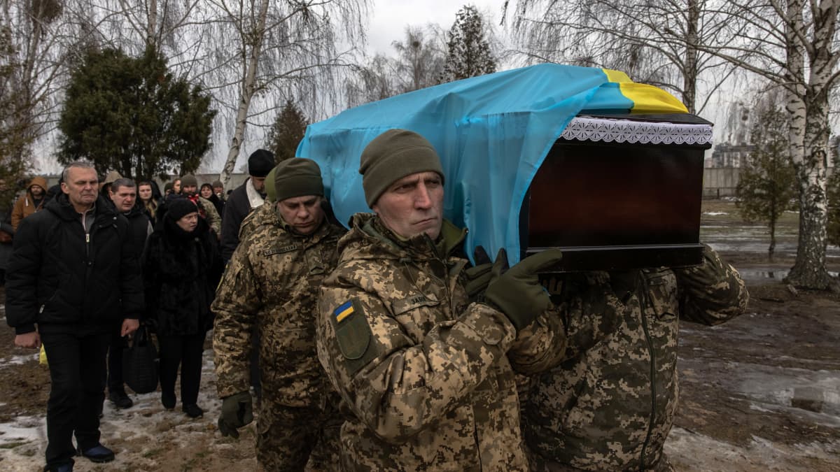 Soldater bär på en likkista täckt med en ukrainsk flagga.