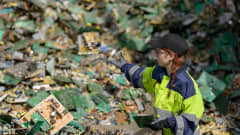 Kuusankoski Oy:n työntekijä heittää elektroniikkajätettä jätekasaan.