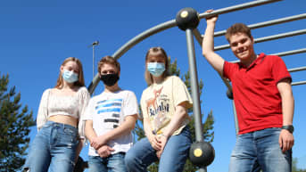 Neljä nuorta poseeraa kiipeilytelineen juurella.