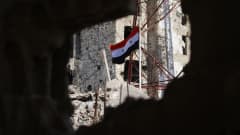 Syyrian lippu liehuu raunioissa.