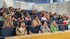 Ukrainalaisia istumassa Peltosaaren koulun auditoriossa kuuntelemassa infotilaisuutta.