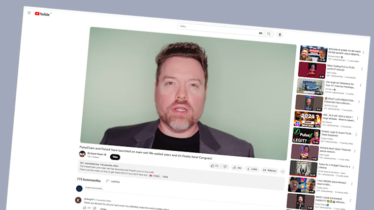 Screen shot taken from YouTube showing a bearded man with a grey suit, talking.