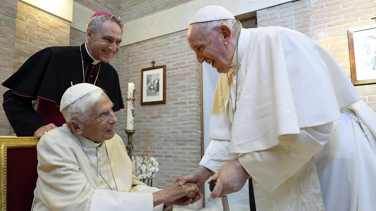 Seisova Paavi Franciscus kättelee istuvaa ex-paavi Benedictusta.