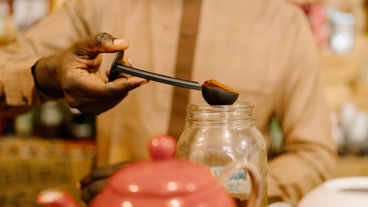 Moussa Niang mittaa kahvia purkista.