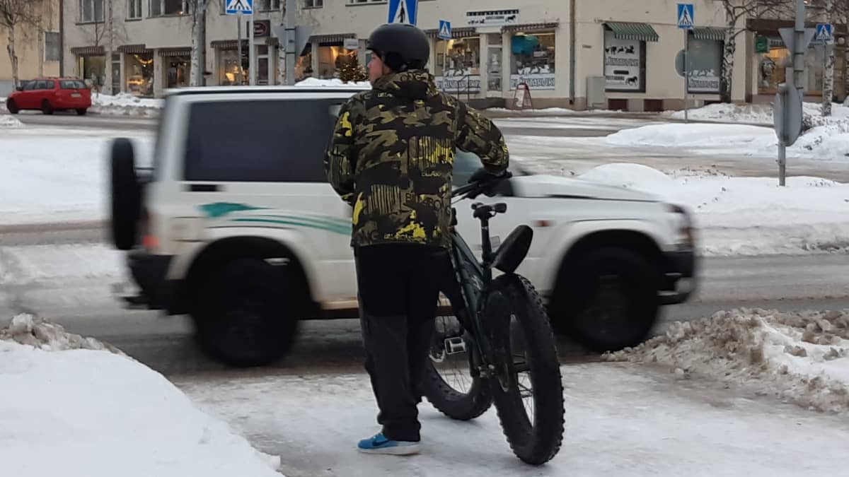 Pyöräilijä odottaa suojatien edessä Nurmeksen keskustassa.