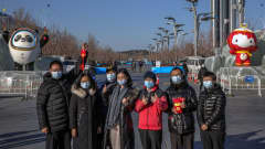 Joukko kiinalaisturisteja poseeraa olympiamaskottien edessä.