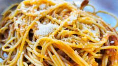 Lautasellinen keitettyä spagettia, jonka päällä on parmesaania.