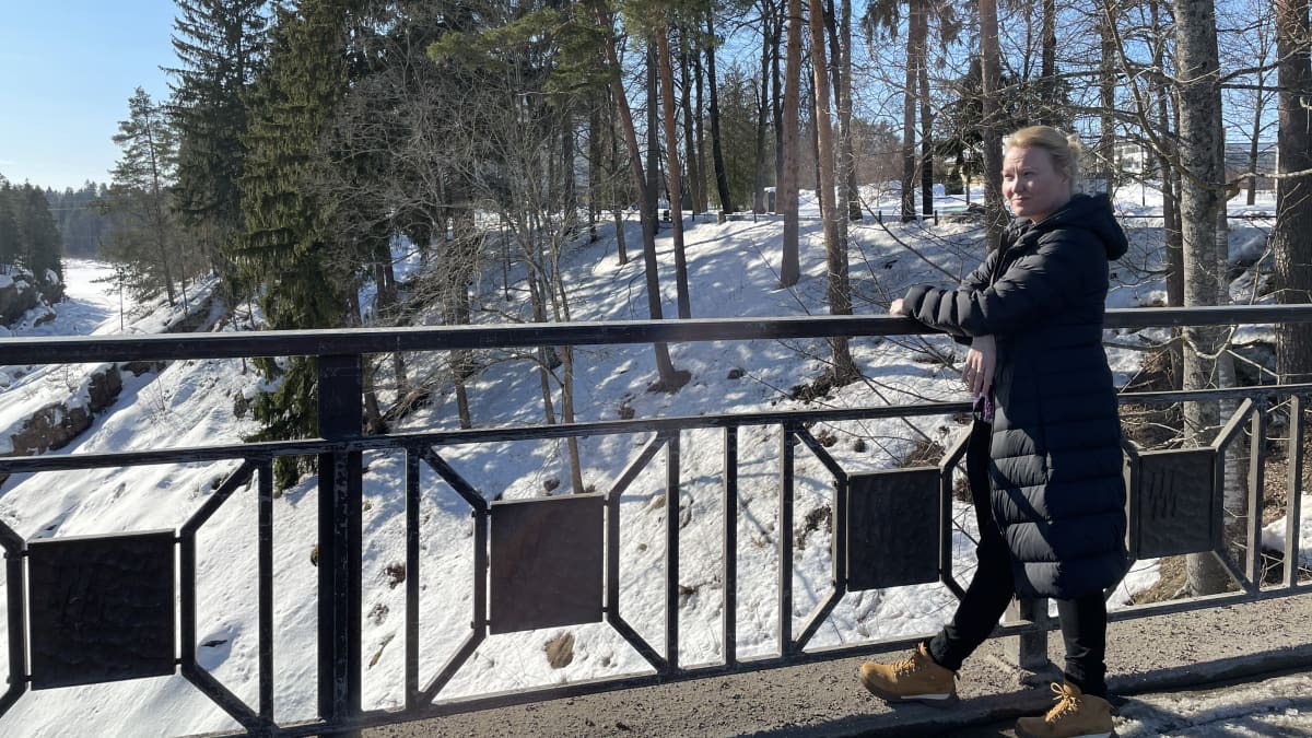 Mari Markkanen nojaa kaiteeseen Imatrankosken sillalla. Luminen maisema. 
