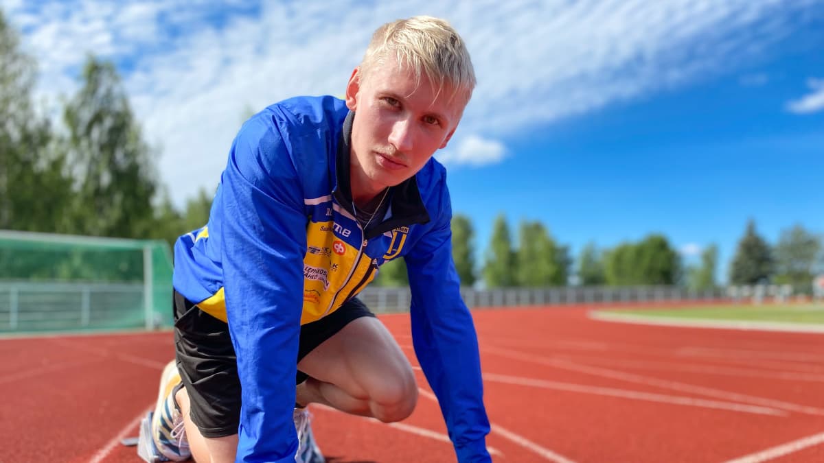 Vaaleahiuksinen, siniseen juoksutakkiin pukeutunut Samuli Samuelsson valmiina lähtemään juoksuun Ikaalisten kentällä. Taustalla näkyy urheilukenttää ja sinistä taivasta.