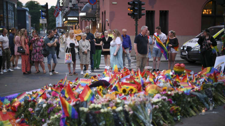 Ihmisiä on kerääntynyt kukin ja Pride-lipuin koristeltuun kadunkulmaan.