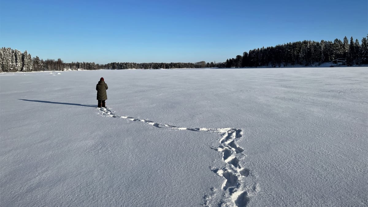 Nainen kävelee järven jäällä.