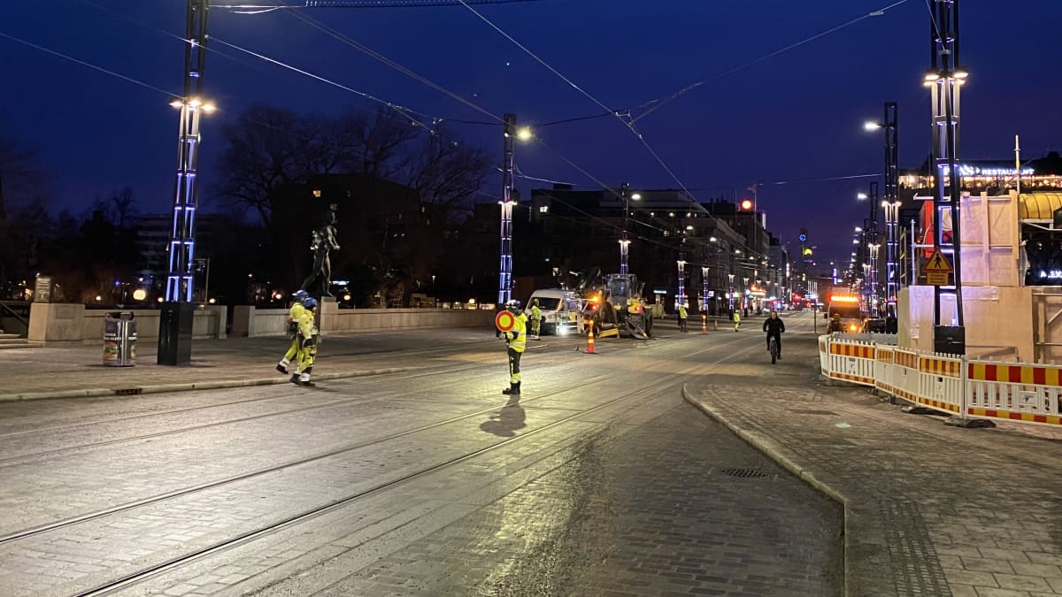 Keltaiseen huomioiasuun pukeutunut ihminen näyttää pysäytymismerkkiä Tampereen Hämeensillalla.