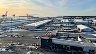 Wide view of Vuosaari Harbour in Helsinki, with paved roads, buildings, vehicles, with the sea in the far distance.