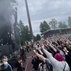 Ihmiset seuraavat lavan edessä yhtyeen keikkaa festivaaleilla.