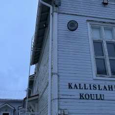 Lähikuva puurakenteisesta koulurakennuksesta, jonka julkisivussa lukee Kallislahden koulu.