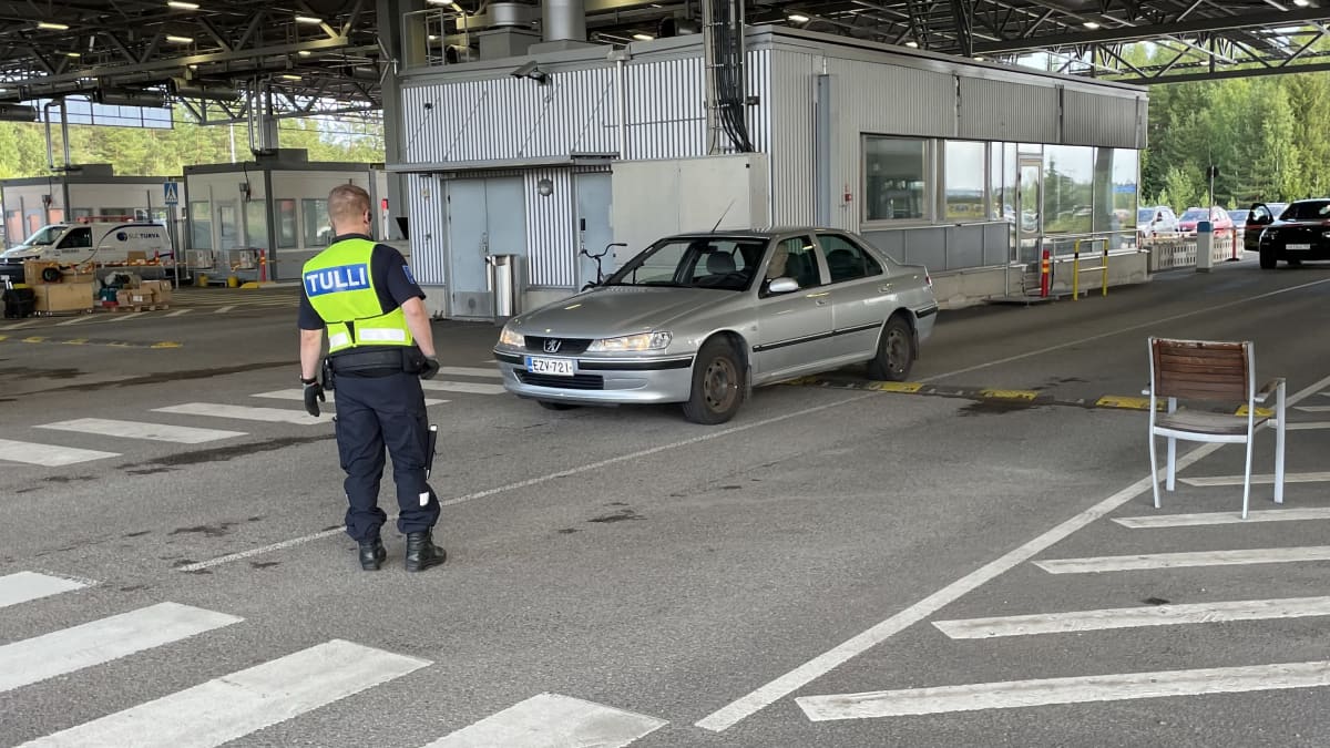 Tullimies seisoo auton edessä, joka on raja-asemalla. 