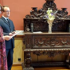 Vasemmalla kaksi henkilöä pitää puhetta oikealla puolella olevalle henkilölle.