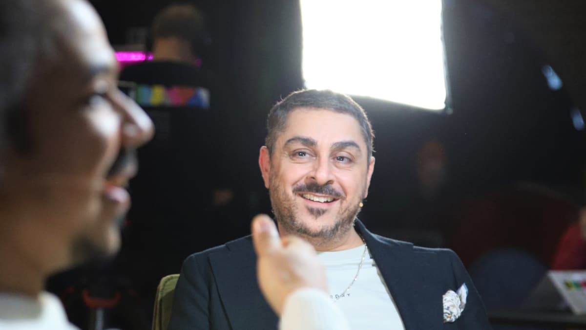 Arman Alizad istuu nojatuolissa ja katsoo hymyillen Sean Ricksiä. Ricks on etualalla epäskarppina ja elehtii käsillään.