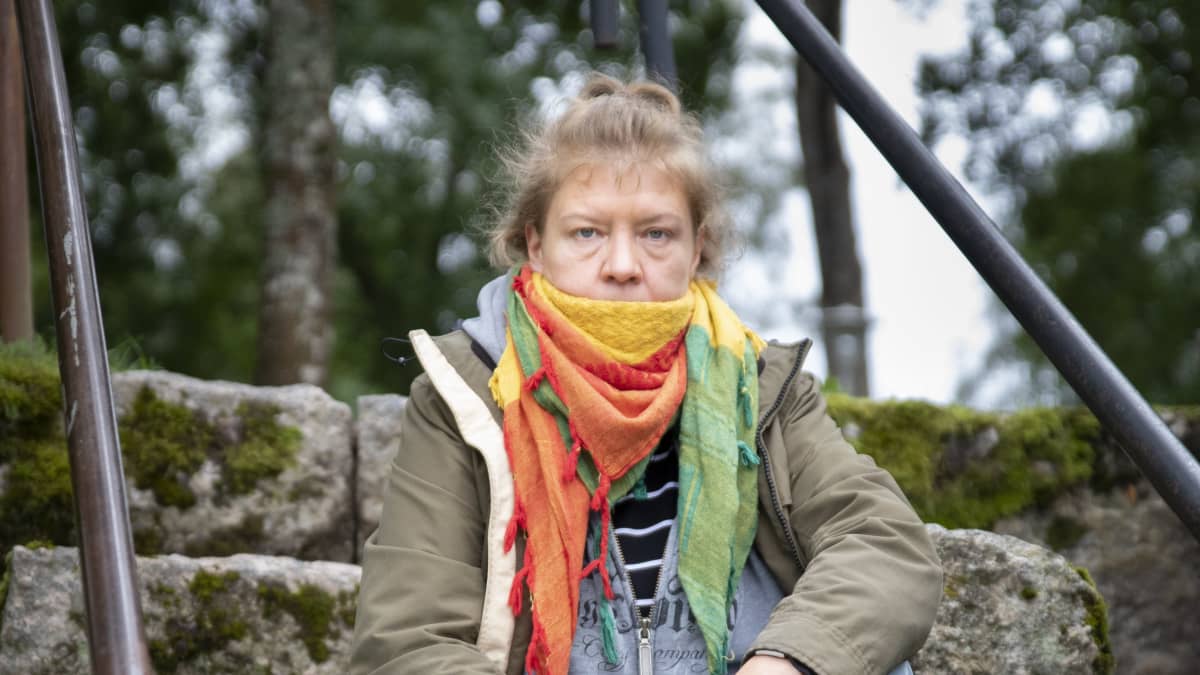 Pirjo Koski istuu kiviportailla.