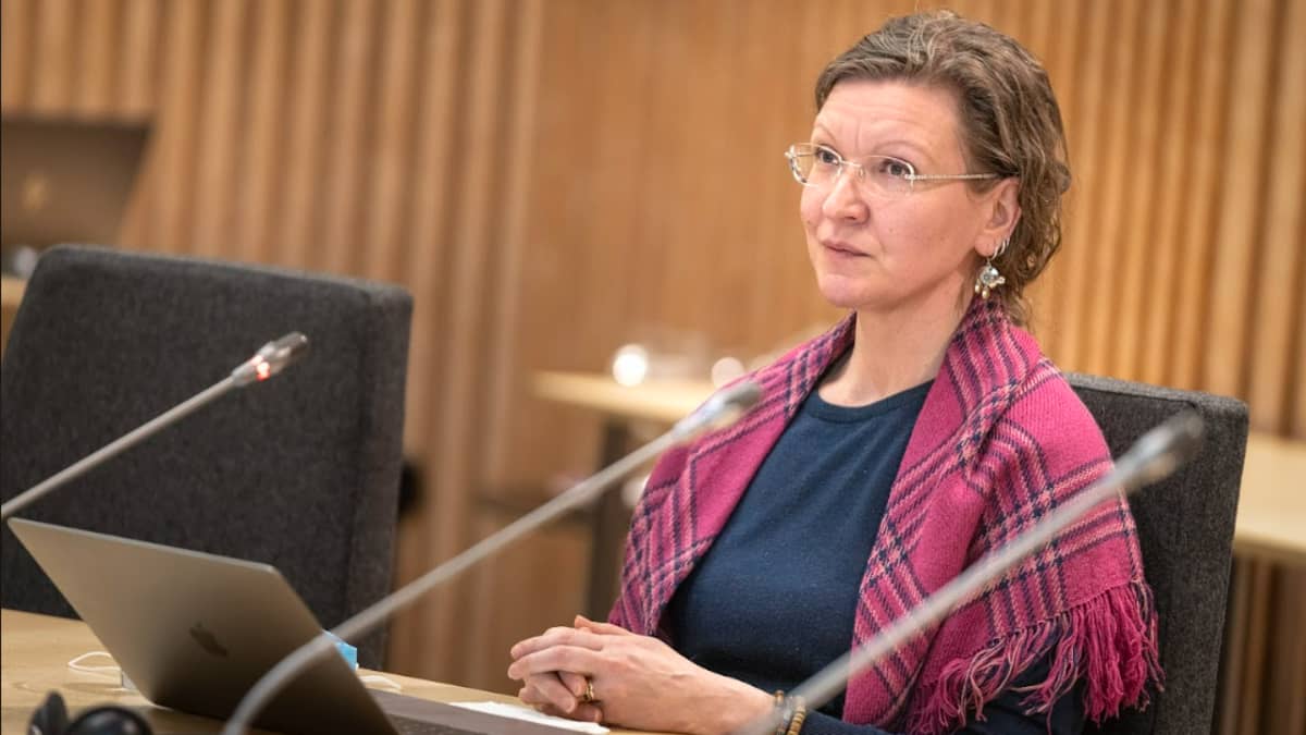 Miina Seurujärvi istuu kokoushuonessa edessään mikrofoni ja läppäri.  