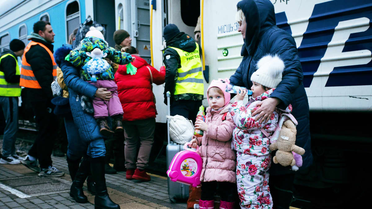 Pakolaisia nousemassa junaan Puolan Chelmissä.