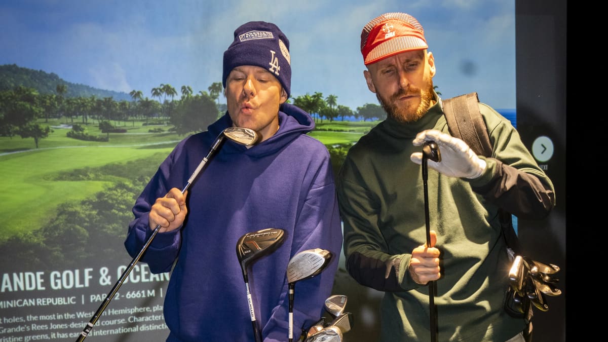 Rap-duo JVG:n Ville-Petteri Galle ja Jare Joakim Brand tutkailevat mailojaan Salmisaari Golfin Golfsimulaattorissa.