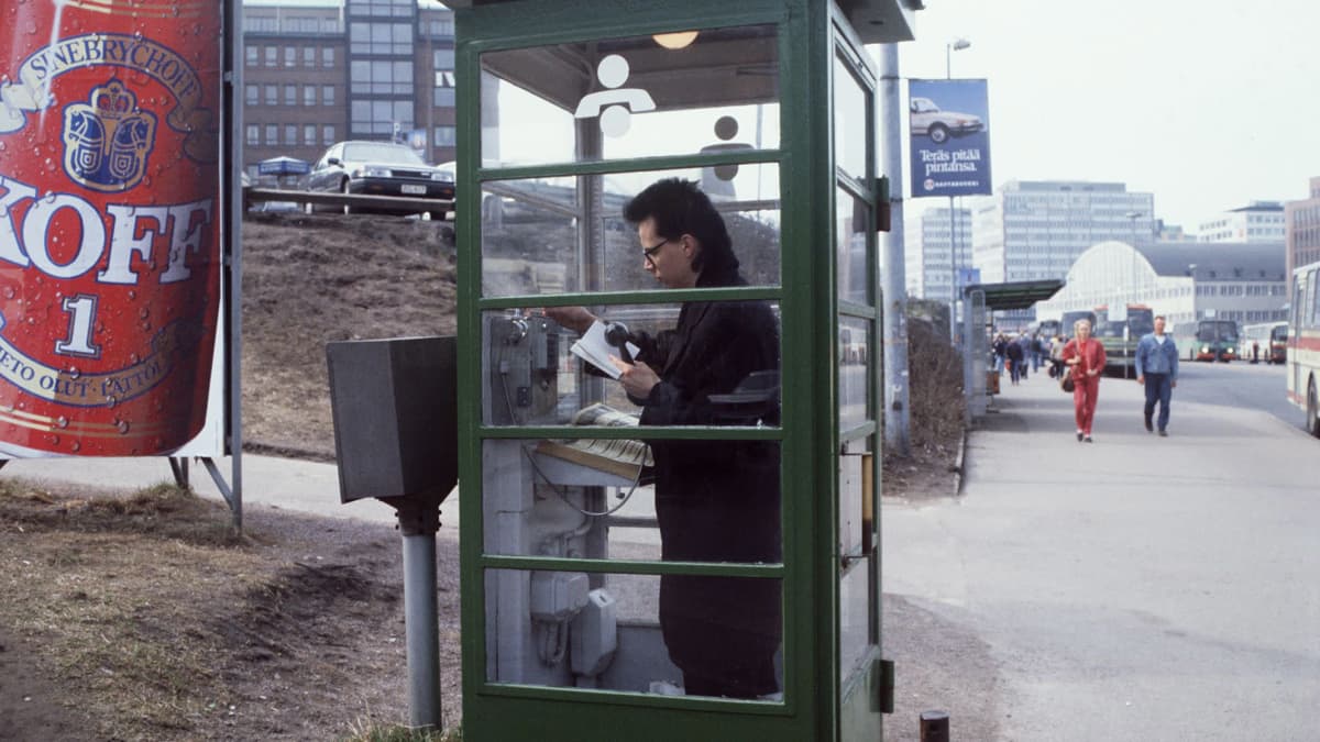 Nuori mies soittamassa puhelinkioskissa vuonna 1990.