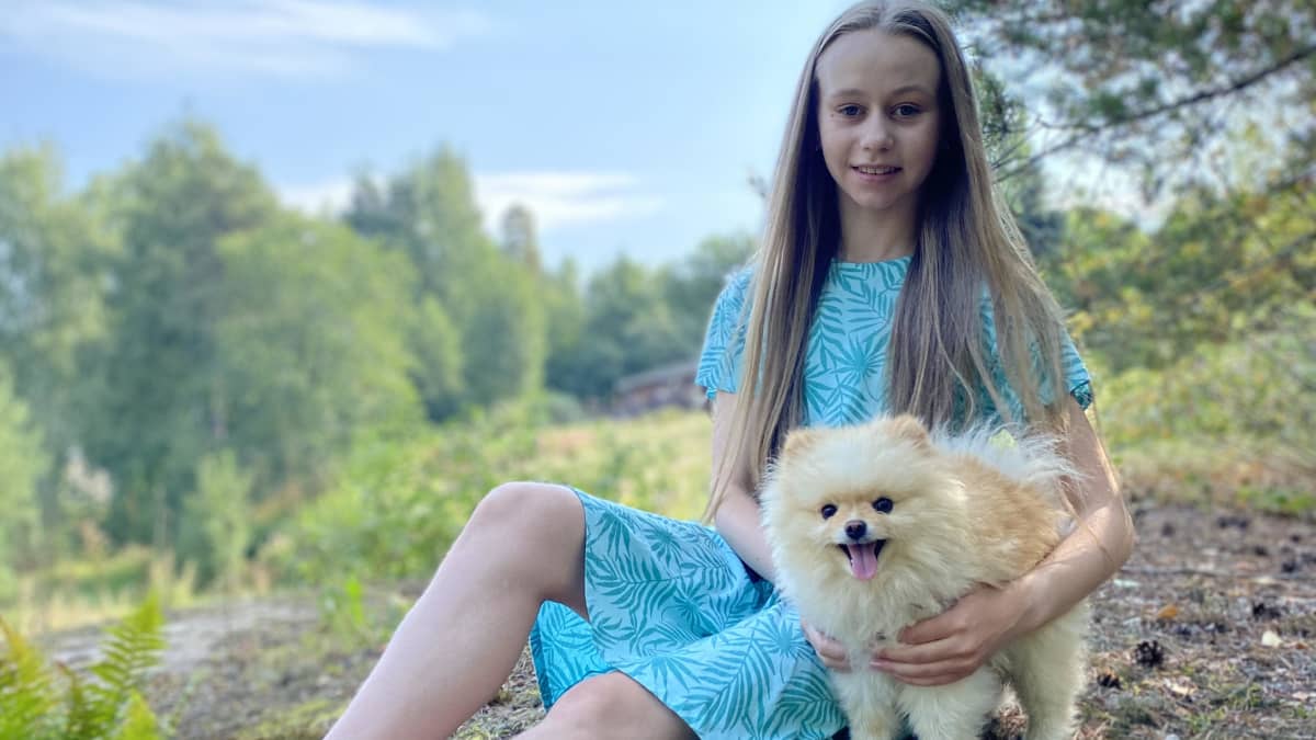 Janna Jyrkinen istuu mättäällä koiransa kanssa.