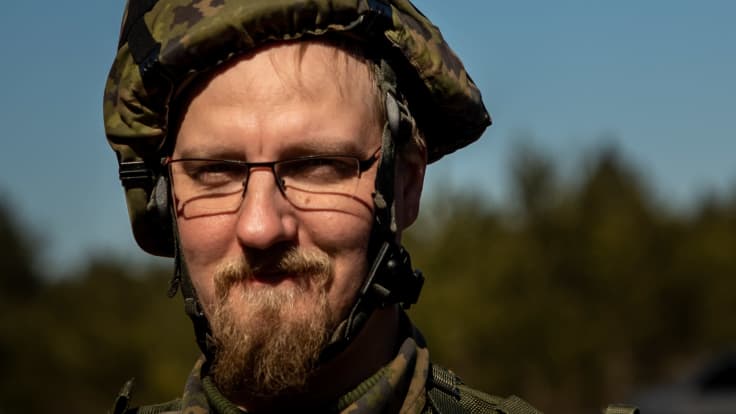 Joni Koivu katsoo kameraan lähikuvassa armeija-asussa. Koivulla on kypärä päässä ja parta. 