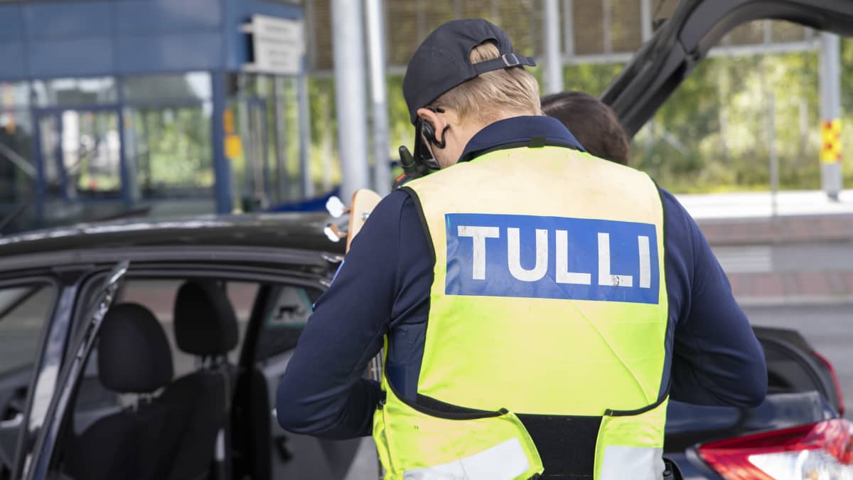Tullimies tutkii Venäjälle menevän matkustajan papereita Niiralan raja-asemalla. 